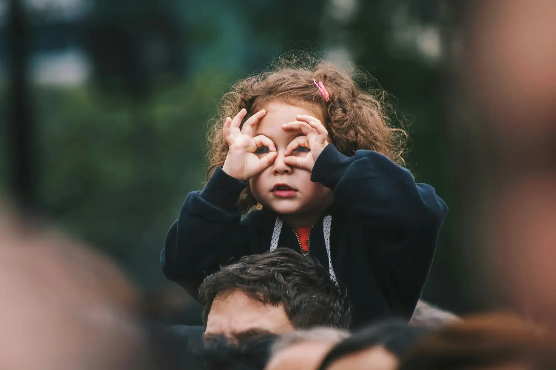 Child making binocular hands, peering out playfully