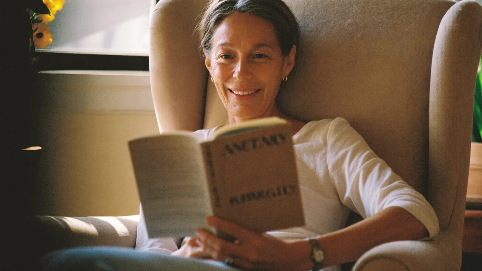 Older woman reading a book comfortably in natural light