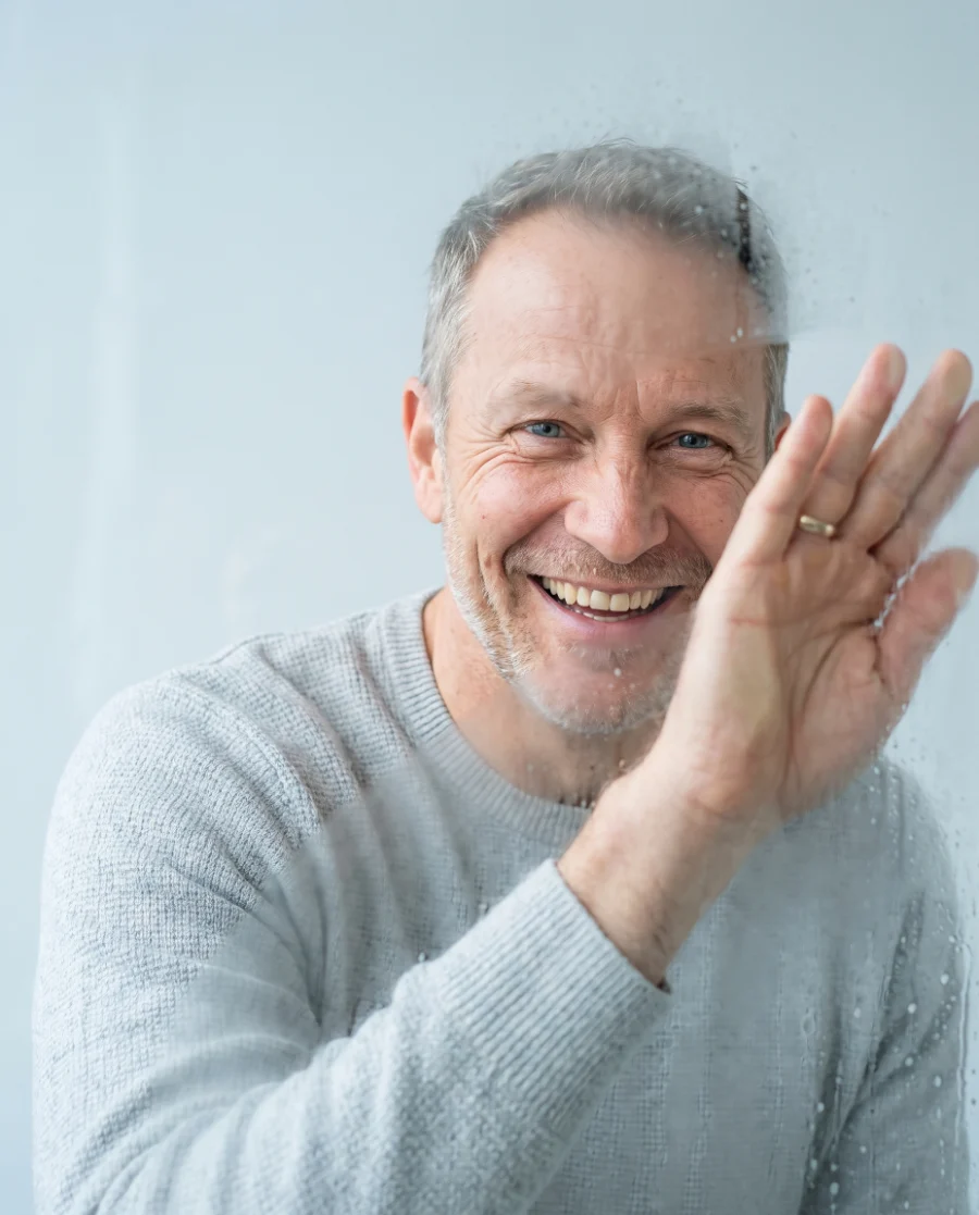 Smiling man wiping a fogged window clear