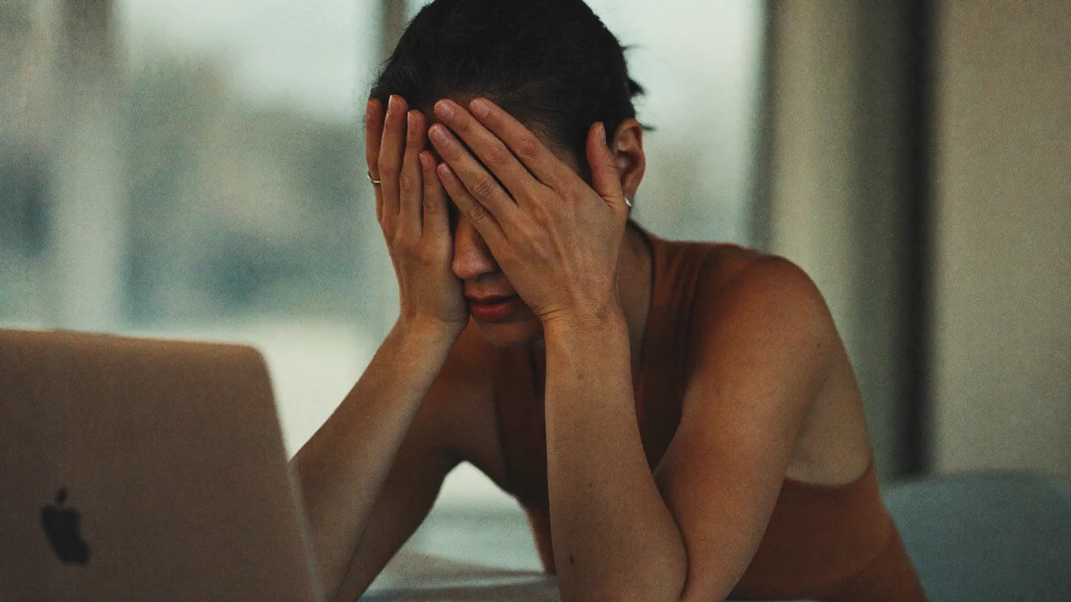 A professional at a desk rubbing tired eyes after a long screen day.