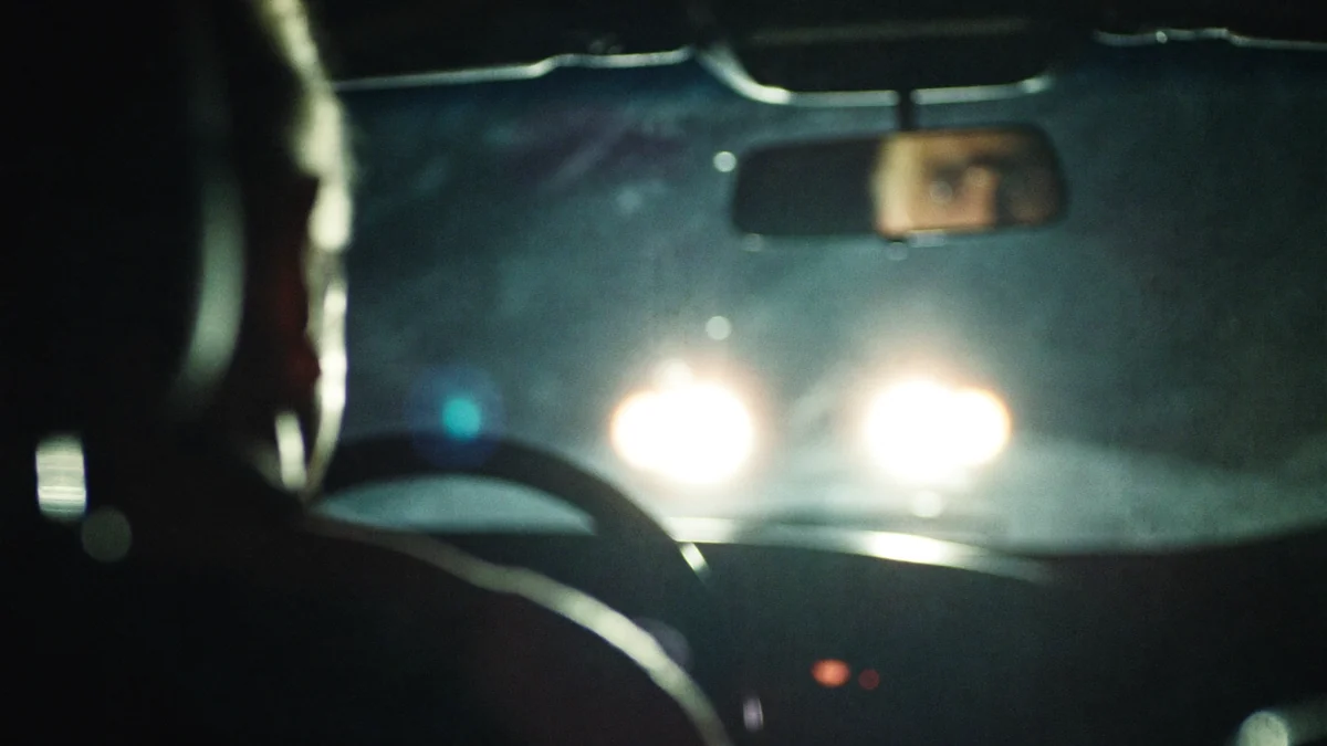 View through a windshield at night with oncoming headlights blooming into halos